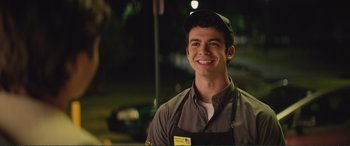 Movie still from “Love, Simon” (2018), directed by Greg Berlanti – A man wearing an apron and a hat smiles for the camera; Medium shot, Over the shoulder angle