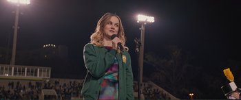 Movie still from “Love, Simon” (2018), directed by Greg Berlanti – A woman is holding a microphone in front of a crowd; Medium shot, Over the shoulder angle