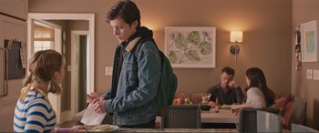 Movie still from “Love, Simon” (2018), directed by Greg Berlanti – A man standing in front of a table with food on top of it; Medium shot, Over the shoulder angle