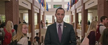 Movie still from “Love, Simon” (2018), directed by Greg Berlanti – A man in a suit and tie standing in a building; Medium shot, Low angle