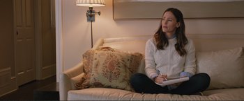 Movie still from “Love, Simon” (2018), directed by Greg Berlanti – A woman sitting on top of a white couch next to pillows; Medium shot, High angle