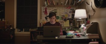 Movie still from “Love, Simon” (2018), directed by Greg Berlanti – A man sitting at a desk using a computer; Medium shot, High angle