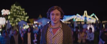 Movie still from “Love, Simon” (2018), directed by Greg Berlanti – A young man standing in front of lights at night; Medium shot, Over the shoulder angle