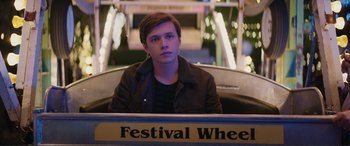 Movie still from “Love, Simon” (2018), directed by Greg Berlanti – A man sitting in front of a festival wheel sign; Medium shot, Over the shoulder angle