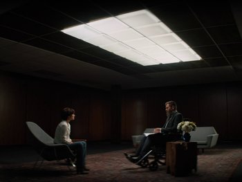 Movie still from “Lucy in the Sky” (2019), directed by Noah Hawley – Two people are sitting in a room with a light shining on them; Wide shot, Over the shoulder angle
