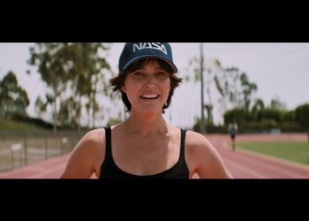 Movie still from “Lucy in the Sky” (2019), directed by Noah Hawley – A woman wearing a nasa hat standing on top of a race track; Medium shot, Over the shoulder angle