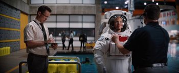 Movie still from “Lucy in the Sky” (2019), directed by Noah Hawley – A woman in a spaceman suit standing next to a pool; Medium shot, Over the shoulder angle
