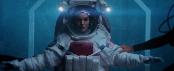 Movie still from “Lucy in the Sky” (2019), directed by Noah Hawley – A woman in a spacesuit is holding a book; Medium shot, Overhead angle