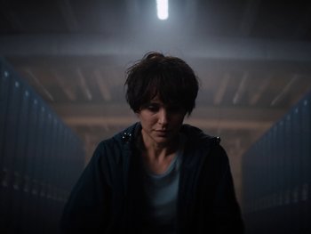 Movie still from “Lucy in the Sky” (2019), directed by Noah Hawley – A person standing in a dark room with a light shining on them; Close Up shot, Low angle