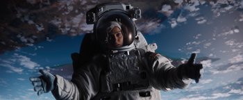 Movie still from “Lucy in the Sky” (2019), directed by Noah Hawley – A person in a spacesuit in front of a cloudy sky; Medium shot, Low angle