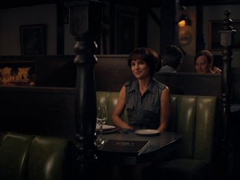 Movie still from “Lucy in the Sky” (2019), directed by Noah Hawley – A woman sitting at a table with a glass of white wine; Medium shot, Over the shoulder angle