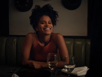 Movie still from “Lucy in the Sky” (2019), directed by Noah Hawley – A woman sitting at a table with a glass of wine; Medium shot, Over the shoulder angle
