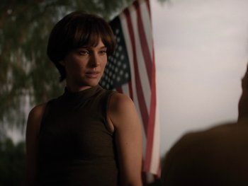 Movie still from “Lucy in the Sky” (2019), directed by Noah Hawley – A woman standing in front of an american flag; Medium shot, Over the shoulder angle