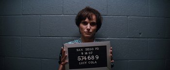 Movie still from “Lucy in the Sky” (2019), directed by Noah Hawley – A woman holding up a sign that says lucy cola; Close Up shot, Over the shoulder angle