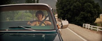 Movie still from “Lucy in the Sky” (2019), directed by Noah Hawley – A woman sitting in the driver's seat of a green car; Medium shot, Low angle