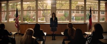 Movie still from “Lucy in the Sky” (2019), directed by Noah Hawley – A woman standing in front of a group of people in front of a window; Wide shot, Over the shoulder angle