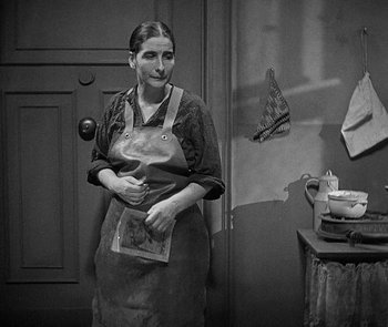 Movie still from “M” (1931), directed by Fritz Lang – A black and white photo of a woman in an apron; Medium shot, High angle