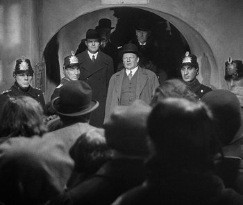 Movie still from “M” (1931), directed by Fritz Lang – A black and white photo of a group of men in a tunnel; Medium shot, Low angle