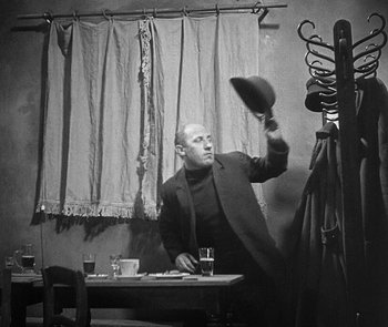 Movie still from “M” (1931), directed by Fritz Lang – A black and white photo of a man throwing a hat; Medium shot, Low angle