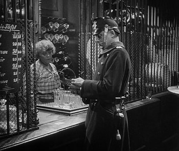 Movie still from “M” (1931), directed by Fritz Lang – A man in a uniform standing in front of a woman; Medium shot, Low angle