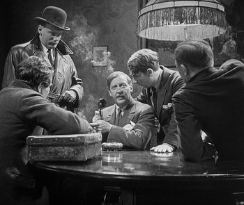 Movie still from “M” (1931), directed by Fritz Lang – A black and white photo of a group of men sitting at a table; Medium shot, Over the shoulder angle