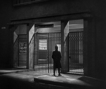 Movie still from “M” (1931), directed by Fritz Lang – A man standing in front of an iron gate; Extreme Wide shot, Low angle