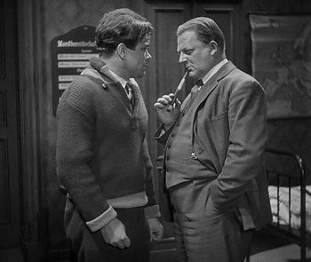 Movie still from “M” (1931), directed by Fritz Lang – Two men are standing next to each other talking; Medium shot, Over the shoulder angle