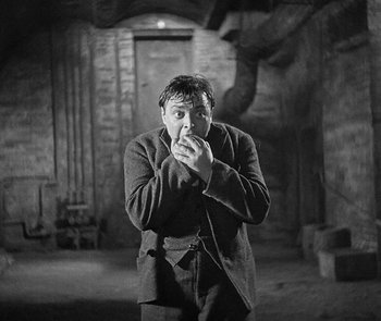Movie still from “M” (1931), directed by Fritz Lang – A black and white photo of a man eating something; Medium shot, High angle