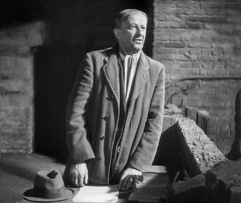 Movie still from “M” (1931), directed by Fritz Lang – An older man standing in front of a brick wall; Medium shot, Low angle