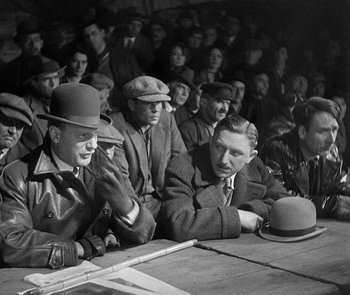 Movie still from “M” (1931), directed by Fritz Lang – A black and white photo of men sitting at a table; Medium shot, High angle