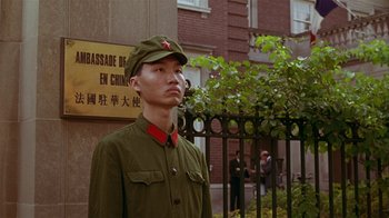 Movie still from “M. Butterfly” (1993), directed by David Cronenberg – A man in a military uniform standing in front of a building; Medium shot, Low angle