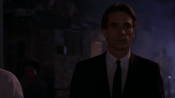 Movie still from “M. Butterfly” (1993), directed by David Cronenberg – A man wearing a suit and tie standing in the dark; Close Up shot, Low angle