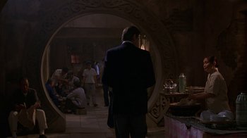 Movie still from “M. Butterfly” (1993), directed by David Cronenberg – A man in a suit standing in front of a mirror; Wide shot, Over the shoulder angle