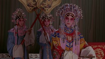 Movie still from “M. Butterfly” (1993), directed by David Cronenberg – A couple of people that are standing up in a room; Medium shot, Low angle
