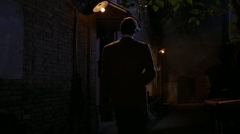 Movie still from “M. Butterfly” (1993), directed by David Cronenberg – A man in a suit walking down a dark street; Wide shot, Low angle