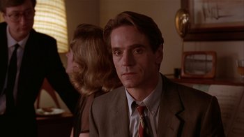 Movie still from “M. Butterfly” (1993), directed by David Cronenberg – A person wearing a suit and tie; Close Up shot, Over the shoulder angle