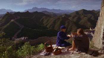 Movie still from “M. Butterfly” (1993), directed by David Cronenberg – Two people sitting on the side of a mountain; Wide shot, High angle