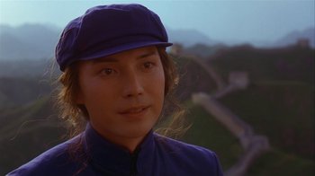 Movie still from “M. Butterfly” (1993), directed by David Cronenberg – A woman wearing a purple hat and a blue jacket; Close Up shot, Over the shoulder angle