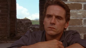 Movie still from “M. Butterfly” (1993), directed by David Cronenberg – A person with his hands on his chest; Close Up shot, Over the shoulder angle