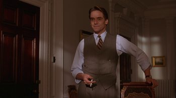 Movie still from “M. Butterfly” (1993), directed by David Cronenberg – A man in a suit and tie holding a cigarette; Medium shot, Low angle