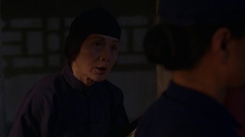 Movie still from “M. Butterfly” (1993), directed by David Cronenberg – An older woman wearing a black hat looking at a younger woman; Close Up shot, Over the shoulder angle