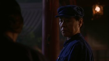 Movie still from “M. Butterfly” (1993), directed by David Cronenberg – An older man wearing a hat and a blue shirt; Close Up shot, Over the shoulder angle