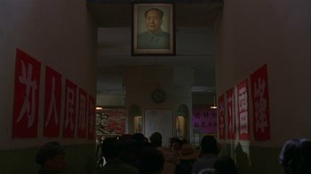 Movie still from “M. Butterfly” (1993), directed by David Cronenberg – A picture of mao zedong hanging above a crowd of people; Wide shot, Low angle
