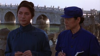 Movie still from “M. Butterfly” (1993), directed by David Cronenberg – Two people standing next to each other near a bridge; Medium shot, Over the shoulder angle