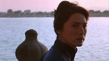 Movie still from “M. Butterfly” (1993), directed by David Cronenberg – A woman standing in front of a body of water; Close Up shot, Over the shoulder angle