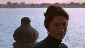 Movie still from “M. Butterfly” (1993), directed by David Cronenberg – A woman standing in front of a body of water; Close Up shot, Over the shoulder angle