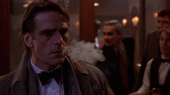 Movie still from “M. Butterfly” (1993), directed by David Cronenberg – A man smoking a cigarette while another man looks on; Close Up shot, Over the shoulder angle