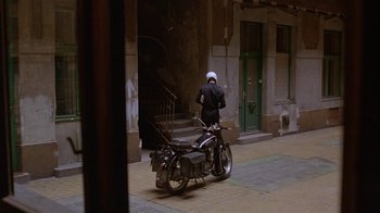 Movie still from “M. Butterfly” (1993), directed by David Cronenberg – A person on a motorcycle on the sidewalk; Wide shot, High angle