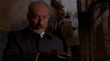 Movie still from “M. Butterfly” (1993), directed by David Cronenberg – A man in a trench coat holding a wallet; Medium shot, Low angle