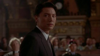 Movie still from “M. Butterfly” (1993), directed by David Cronenberg – A person wearing a suit and tie; Close Up shot, Low angle